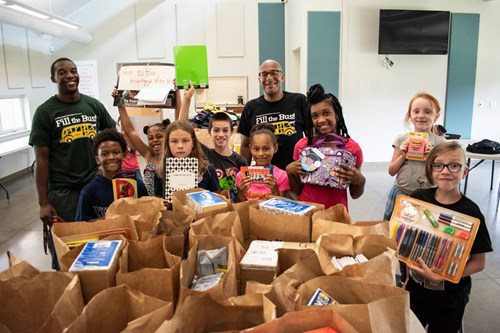 Students posing with Center for Community Engaged Learning staff in 2022 and holding donations from the Fill the Bus campaign.