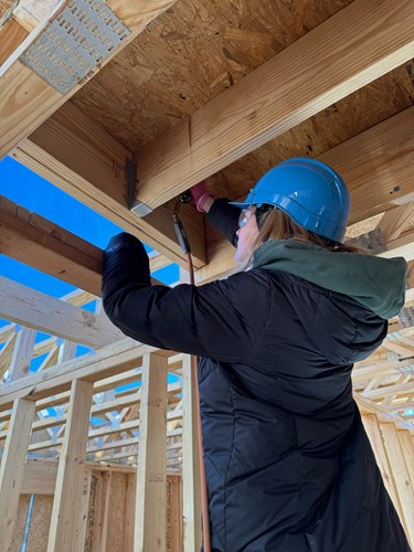An ASB participant on the Move, Play, Serve experience working on the rafter of a house under construction.