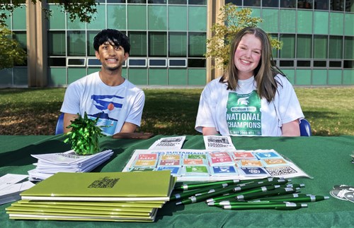 2025-2026 Spartan Volunteer Leaders Aarav Contractor and Haylie Pohlman tabling with a set of UN Sustainable Development Goal stickers at an event with Spartan Compass, a first-year program introducing students to campus.