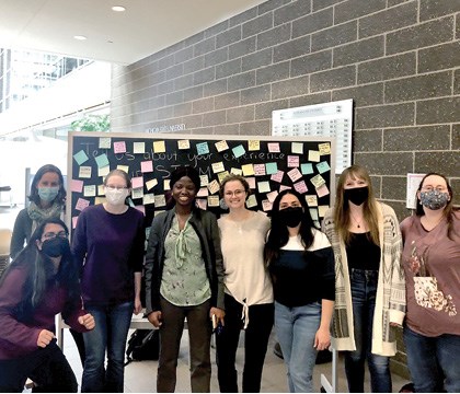 Graduate Students in front of a reflection board at a community event