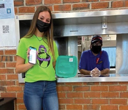 Student showing one of the resuable containers being piloted for mobile orders in the dining halls