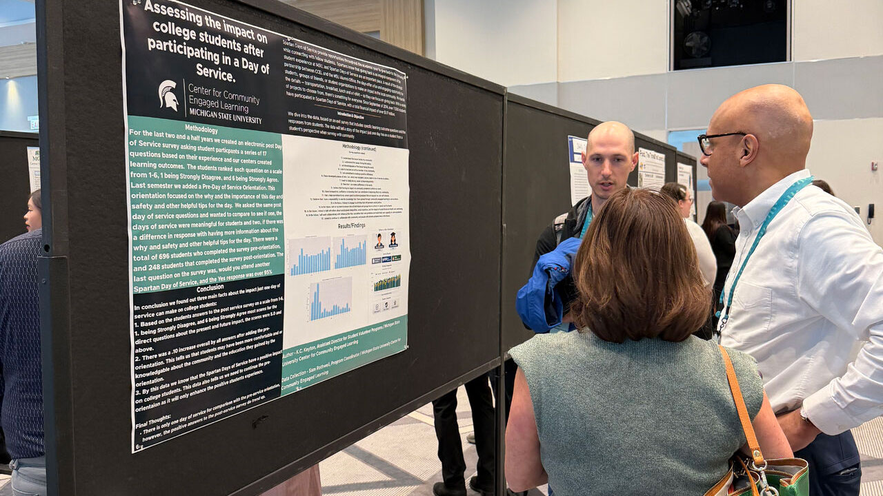 CCEL assistant director K.C. Keyton (right) presents his poster about 'Assessing the impact on college students after participating in a day of service' at the Campus Compact conference (Compact26) in Chicago.
