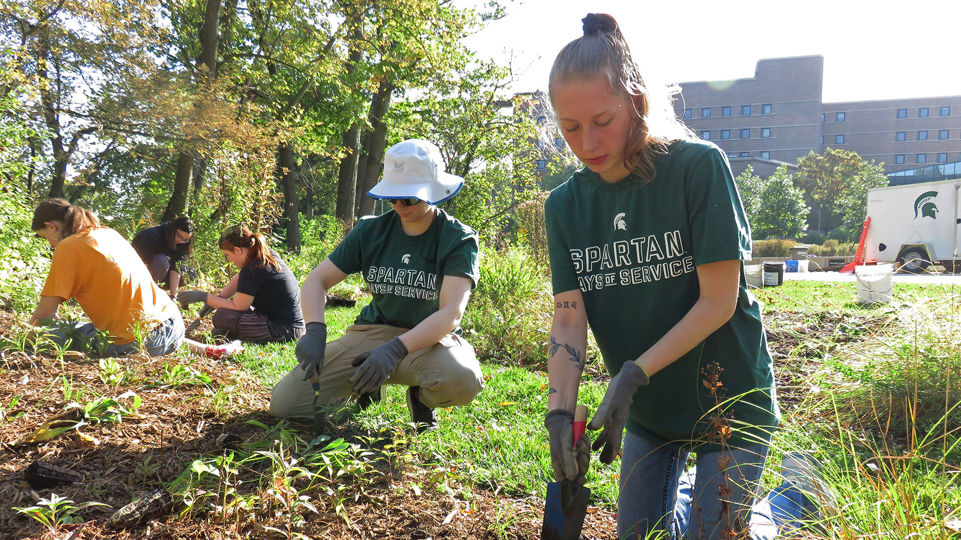 Fall Day of Service volunteers with the MSU Pollinator Gardens planting Michigan native plant species by the Red Cedar River