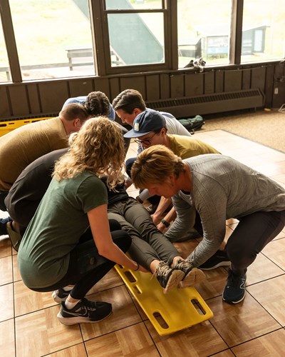 Rural community health students practice lifting a fellow student onto a gurney during their field skills elective course.
