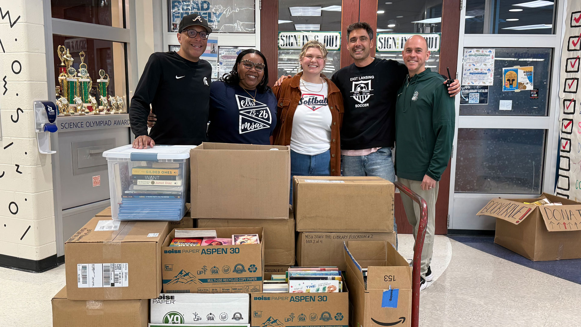 CCEL assistant director K.C. Keyton (left) and MSU Alumni Office director of student engagement Dan DiMaggio (right) delivered books donated to the Stuff the Library campaign at East Lansing High School on May 8, 2026.