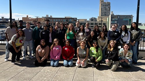 A group photo of the 810 Flint Forward Tour group of MSU students, faculty, and staff on the roof of the Flint Farmers Market, near the CHM Flint Campus.