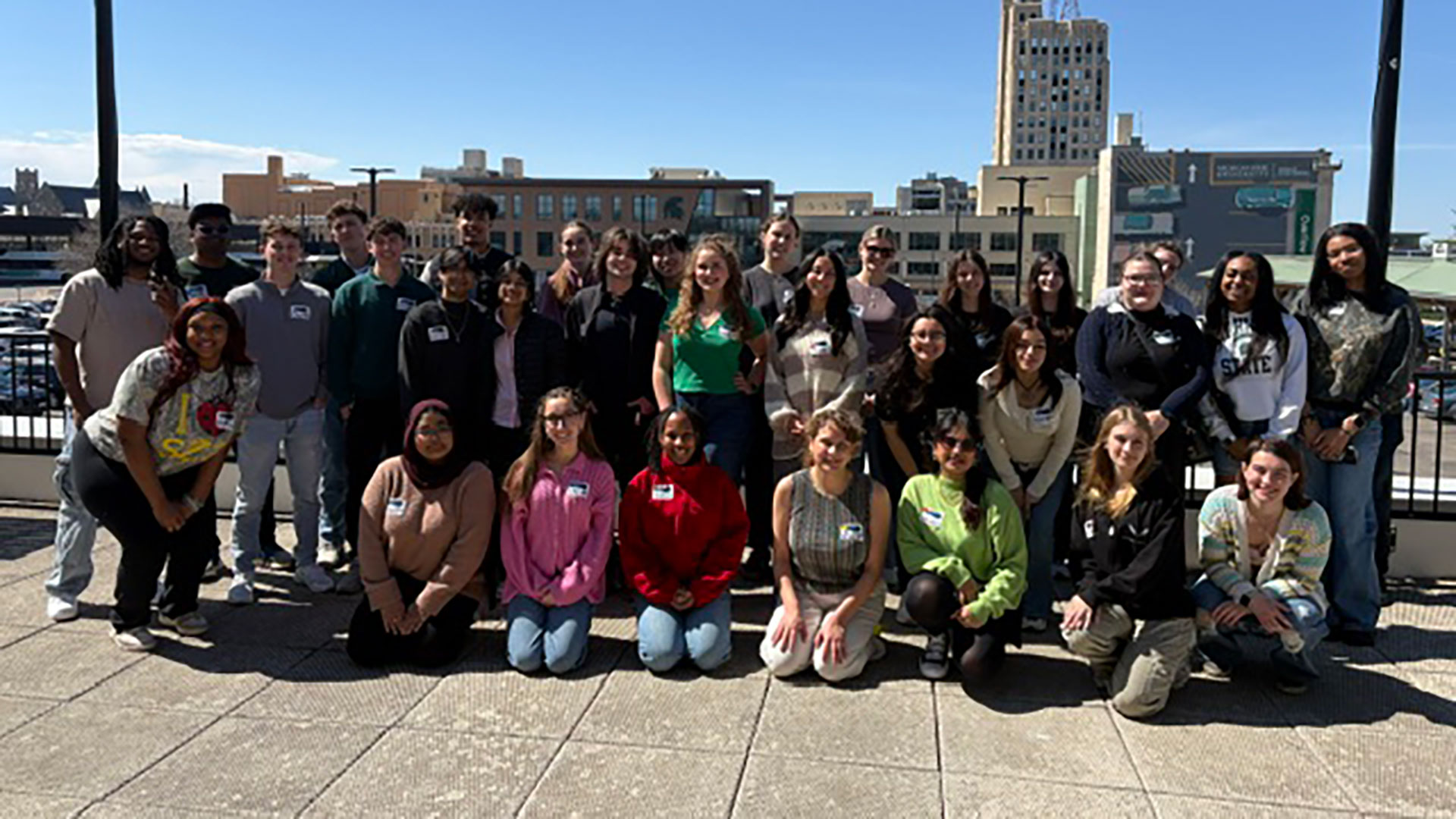 A group photo of the 810 Flint Forward Tour group of MSU students, faculty, and staff on the roof of the Flint Farmers Market, near the CHM Flint Campus.